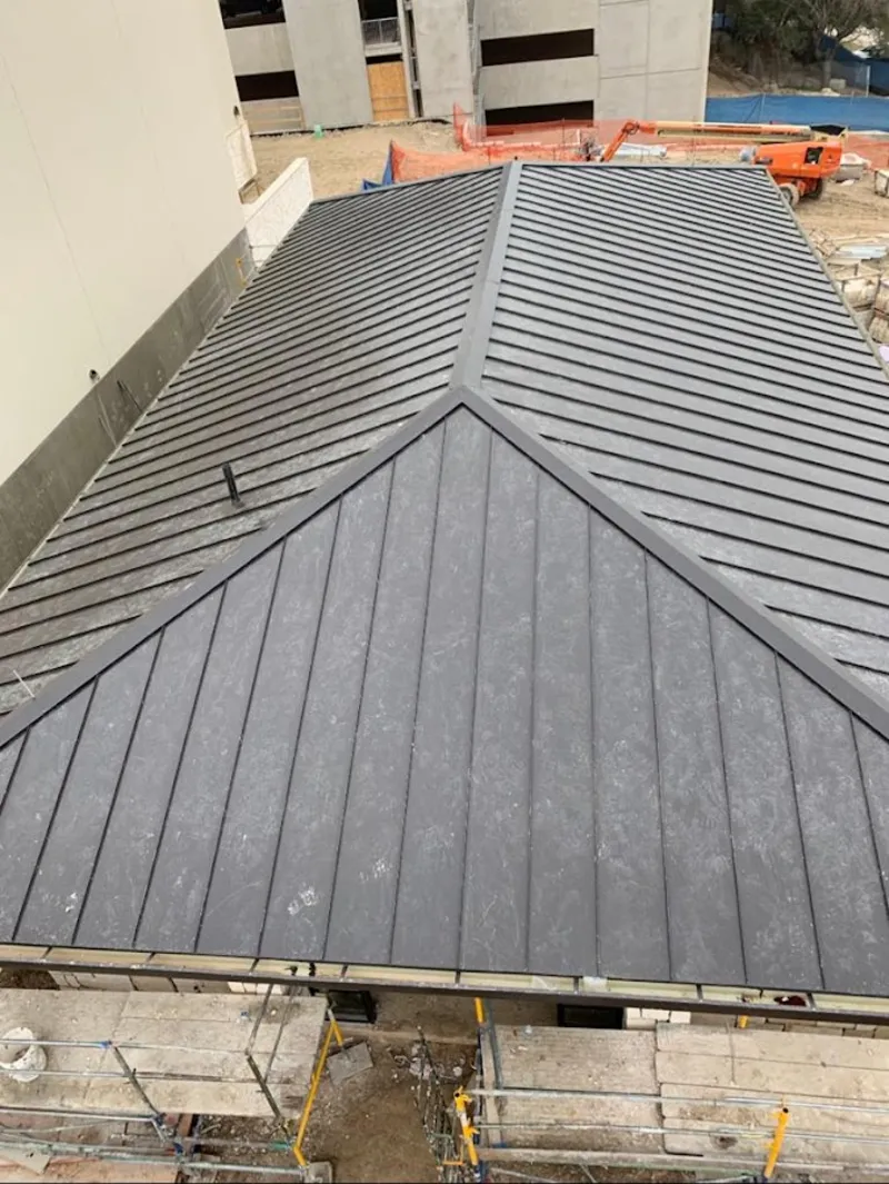 Commercial metal roof construction with crane equipment in Saratoga Springs